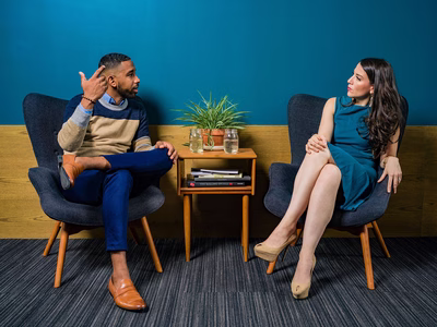 A man and woman having a chat in a relaxed break out area.