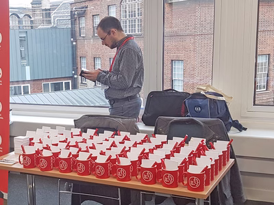 Barry stood by the Real Life Digital merchandise stand at DrupalCamp London 2017.