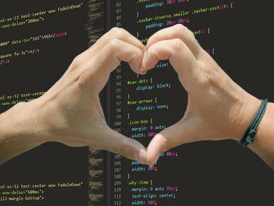 Two hands forming a heart shape with the fingers over a screen of CSS code.