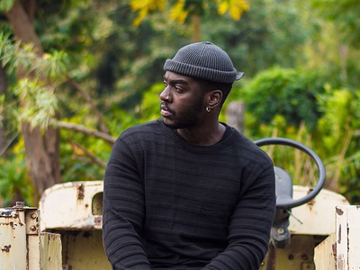 A young african farmer, resting on the back of his pickup.