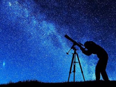 A silhouette of an astronomer on a backdrop of the milky way.