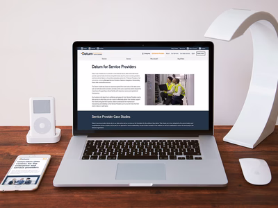 The Service Providers landing page on a MacBook on a desk with an iPod, and iPhone and a piece of modern art.