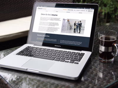 The Enterprise landing page on a MacBook next to a glass of coffee.
