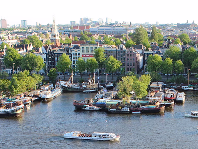 An Amsterdam Panorama - the city from afar with water, land, boats, buildings and trees.