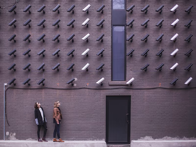 Two people look up at an abundance of CCTV cameras monitoring them.