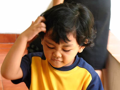 A boy looking very confused and scratching his head.