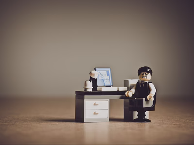 A lego man looking frustrated next to a laptop.