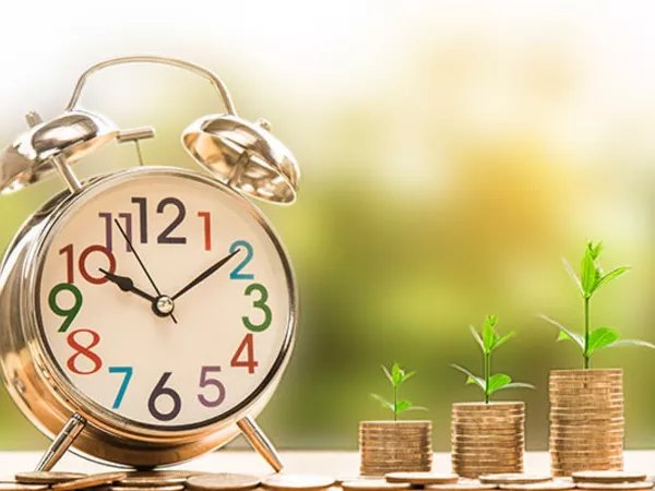 A clock and some coin piles sprouting vegetation - a metaphor for return on investment over time.