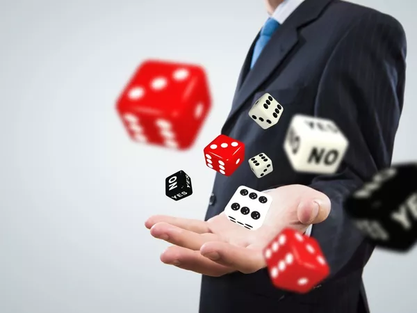 An ambiguous figure in a suit throwing dice towards he camera.