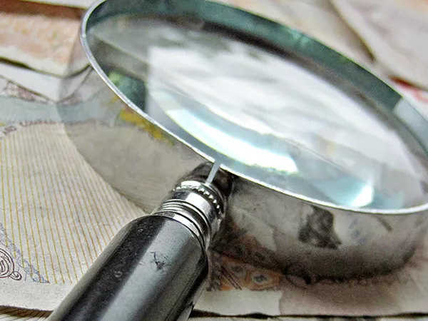 A magnifying glass laid on top of some money.