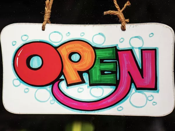 A hand made, brightly coloured sign with the word OPEN.