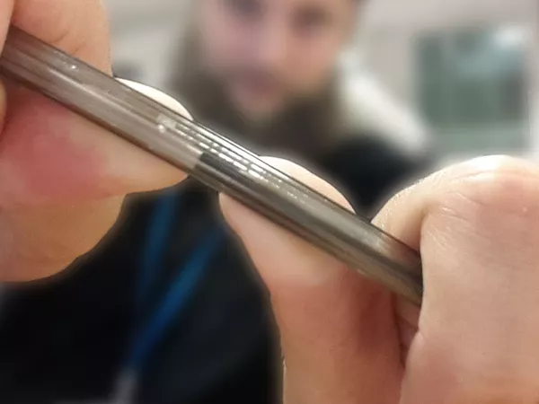 A man is holding a pen up to the camera and is in the process of snapping it in half.