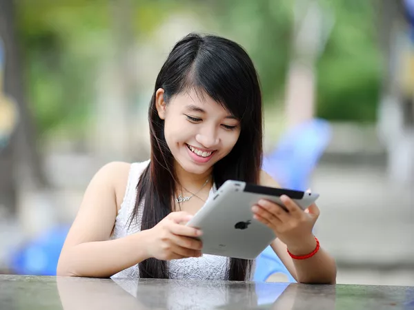 A woman smiling whilst using an ipad.