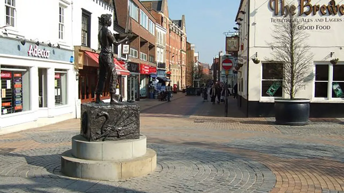 Maidenhead High St. The Western end is pedestrianized. In the foreground is a sculpture called 'Maidenhead Boy'