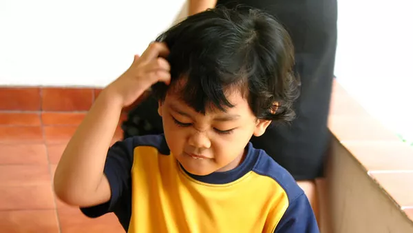 A boy looking very confused and scratching his head.