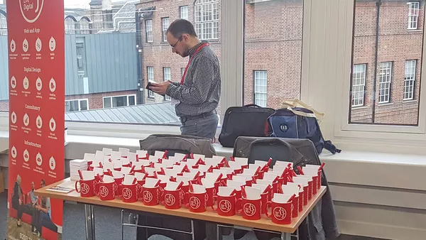 Barry stood by the Real Life Digital merchandise stand at DrupalCamp London 2017.