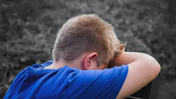 A young boy with blond hair so stressed over his tablet he&apos;s now covering his face with his hands.