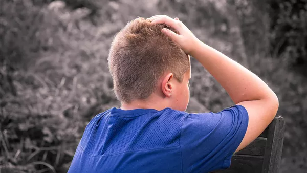 A young boy with blond hair stressing over his tablet.