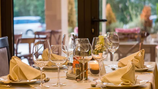 A restaurant table setting, with plates, decorative napkins and wine glasses, all made up ready for diners to arrive.