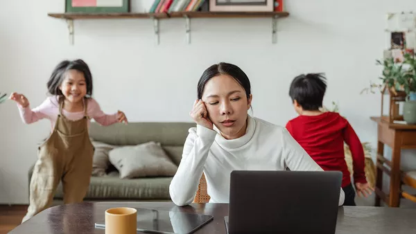 A woman trying to work from home, but struggling due to her restless children running around.