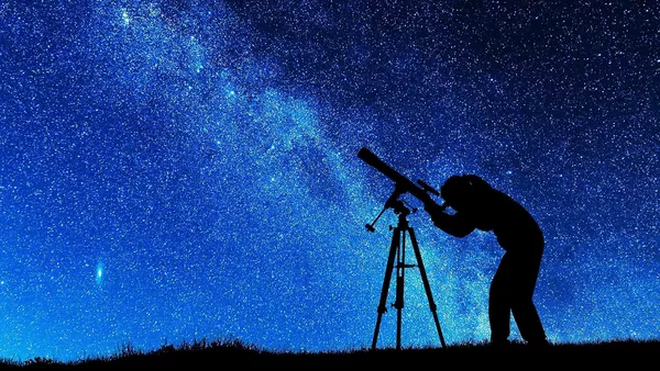 A silhouette of an astronomer on a backdrop of the milky way.