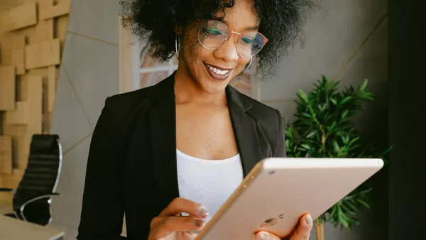 A woman In a black blazer interacting with custom software on an iPad.