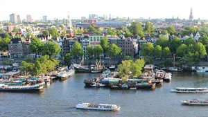 An Amsterdam Panorama - the city from afar with water, land, boats, buildings and trees.