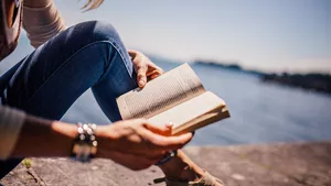 A woman reading a book on a beach.