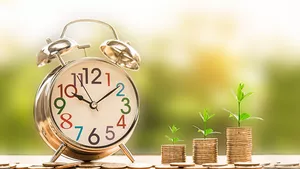 A clock and some coin piles sprouting vegetation - a metaphor for return on investment over time.