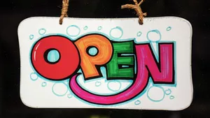 A hand made, brightly coloured sign with the word OPEN.