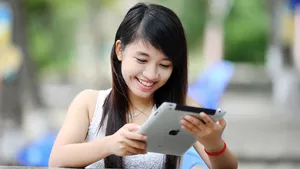 A woman smiling whilst using an ipad.