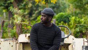 A young african farmer, resting on the back of his pickup.