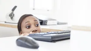 Businesswomen looking out for her boss peeking over desk with apprehesion.
